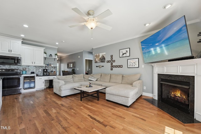 living room with crown molding, a high end fireplace, light wood-type flooring, and wine cooler