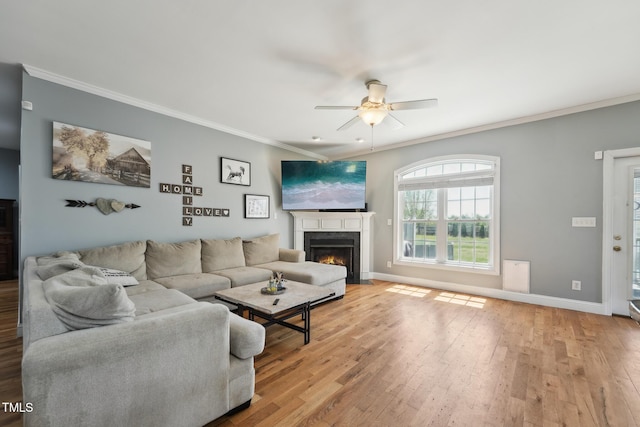 living area with a fireplace with flush hearth, ornamental molding, a ceiling fan, and hardwood / wood-style flooring