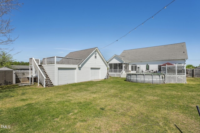 back of house with an outdoor structure, a shed, a sunroom, stairs, and a lawn