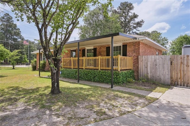 ranch-style home with a front lawn, brick siding, a porch, and fence