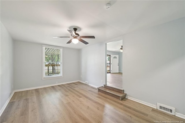 spare room with baseboards, a ceiling fan, wood finished floors, and visible vents