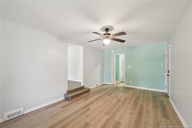 spare room featuring baseboards, a ceiling fan, wood finished floors, and visible vents