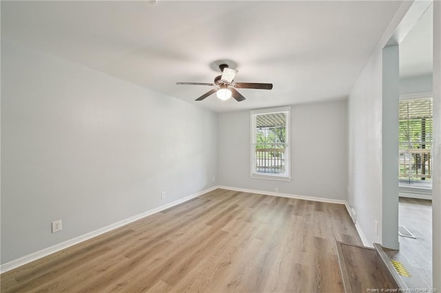empty room featuring light wood finished floors, a ceiling fan, and baseboards