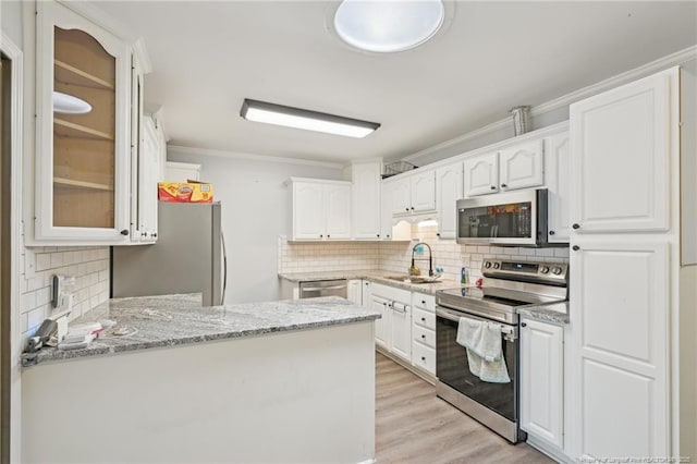 kitchen with white cabinets, stainless steel appliances, a sink, and backsplash