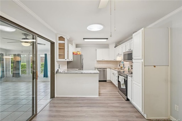 kitchen featuring backsplash, glass insert cabinets, a ceiling fan, and stainless steel appliances