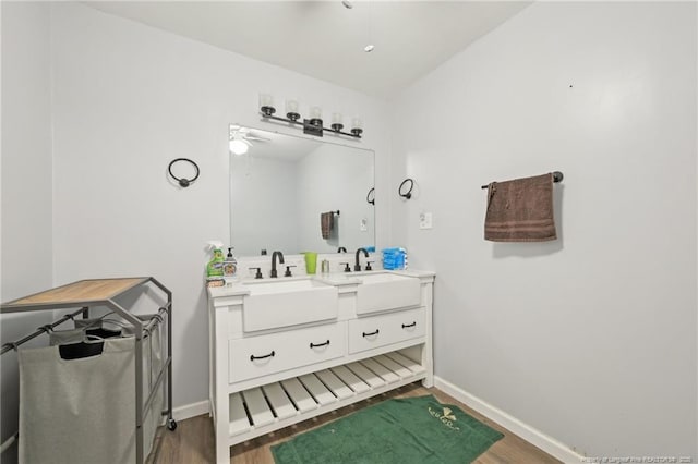 bathroom featuring wood finished floors, baseboards, and a sink