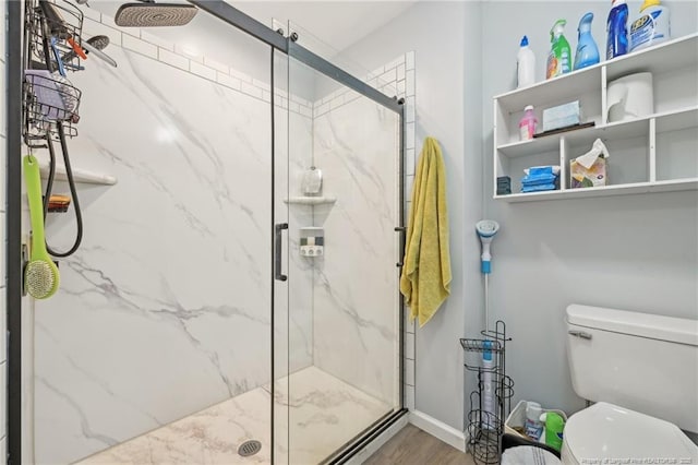 full bath featuring toilet, wood finished floors, a marble finish shower, and baseboards