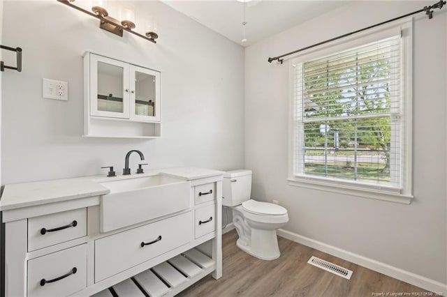bathroom with wood finished floors, baseboards, a healthy amount of sunlight, and toilet