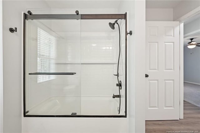 full bath featuring wood finished floors, a ceiling fan, and bath / shower combo with glass door