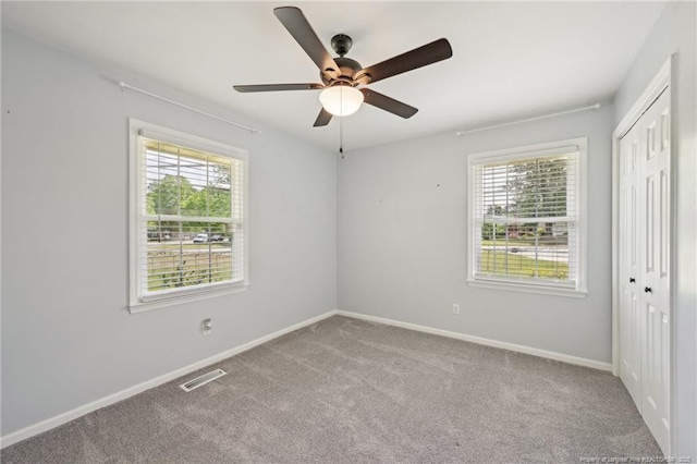 unfurnished bedroom with a closet, ceiling fan, carpet floors, baseboards, and visible vents