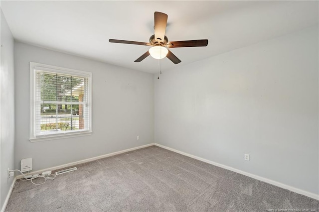 carpeted spare room featuring baseboards, a ceiling fan, and visible vents