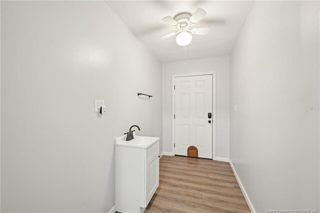 washroom featuring light wood-style floors, baseboards, ceiling fan, and a sink