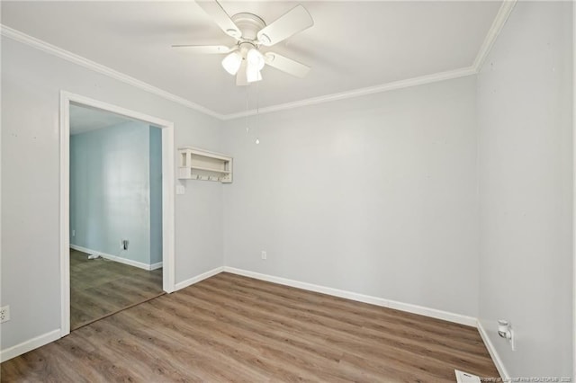 spare room featuring a ceiling fan, baseboards, crown molding, and wood finished floors