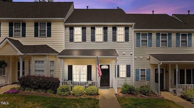 townhome / multi-family property with a porch and roof with shingles