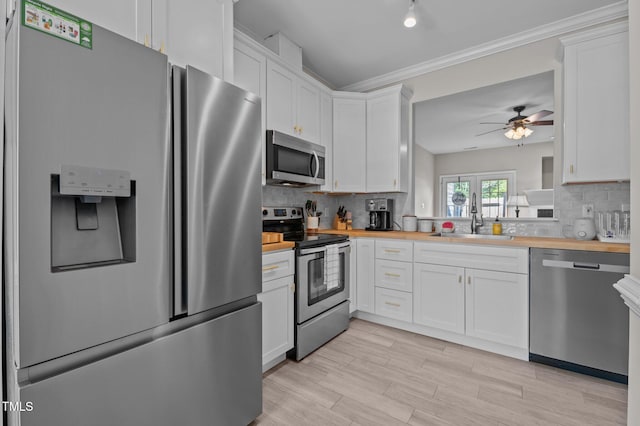 kitchen with ceiling fan, backsplash, a sink, wood counters, and stainless steel appliances