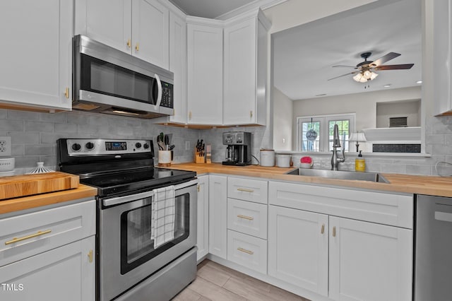 kitchen with ceiling fan, appliances with stainless steel finishes, a sink, wooden counters, and tasteful backsplash