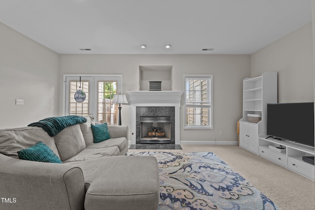 carpeted living area with a premium fireplace, baseboards, visible vents, and recessed lighting