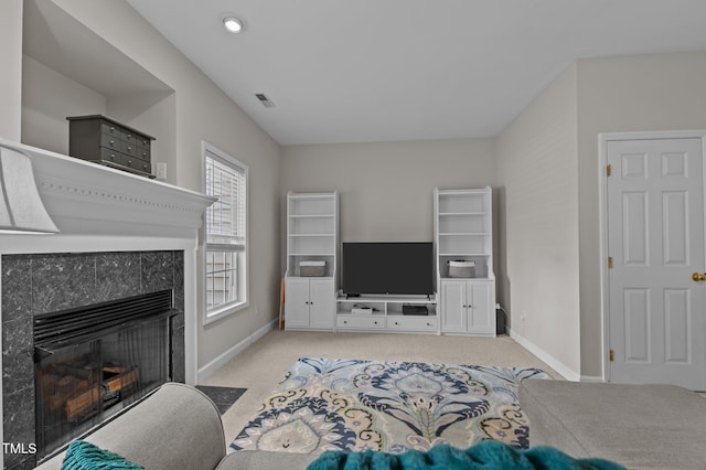 living room with a tiled fireplace, baseboards, carpet floors, and visible vents