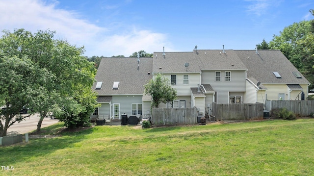 back of house featuring a lawn, fence, and a shingled roof
