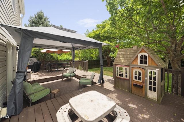 deck with outdoor dining area, fence private yard, a gazebo, an outdoor structure, and a grill