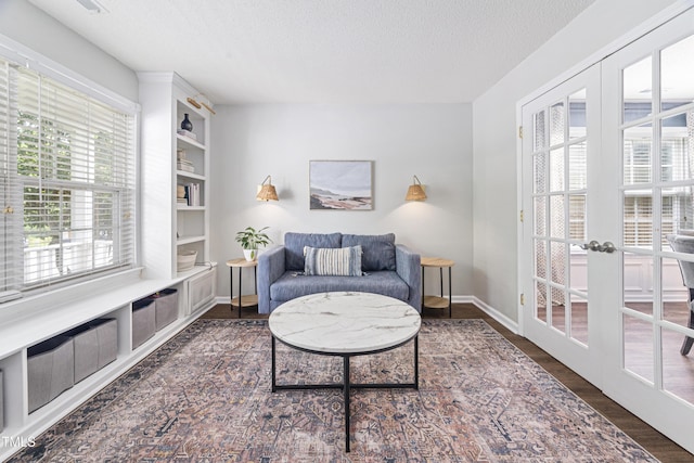 interior space featuring french doors, a textured ceiling, baseboards, and wood finished floors