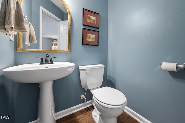 half bathroom featuring toilet, baseboards, and wood finished floors