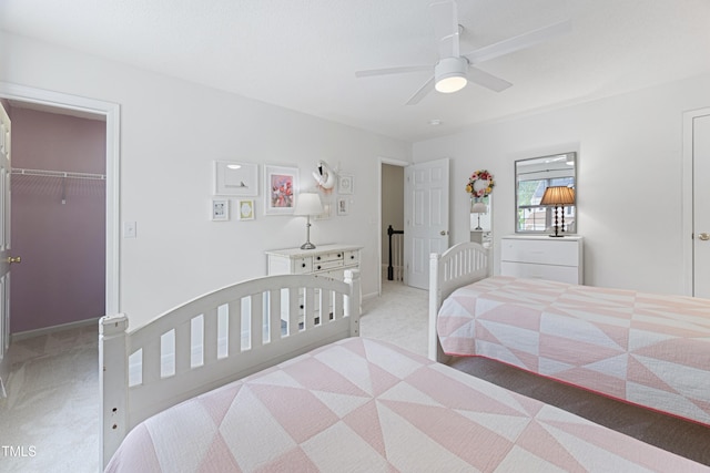 bedroom with light colored carpet, a ceiling fan, a walk in closet, and a closet