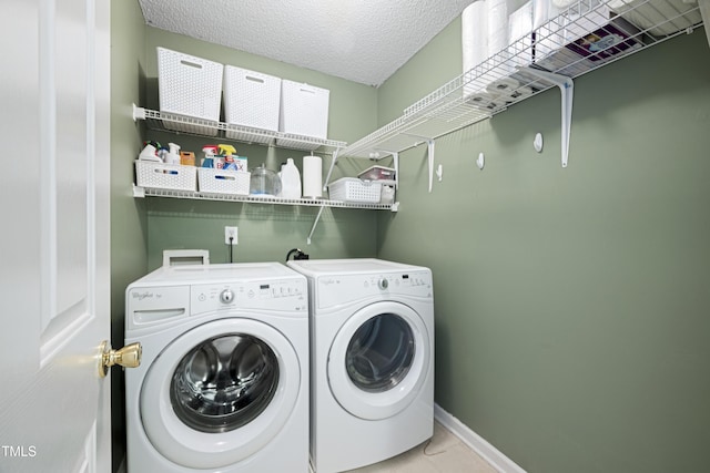 clothes washing area with washer and dryer, laundry area, a textured ceiling, baseboards, and light tile patterned floors
