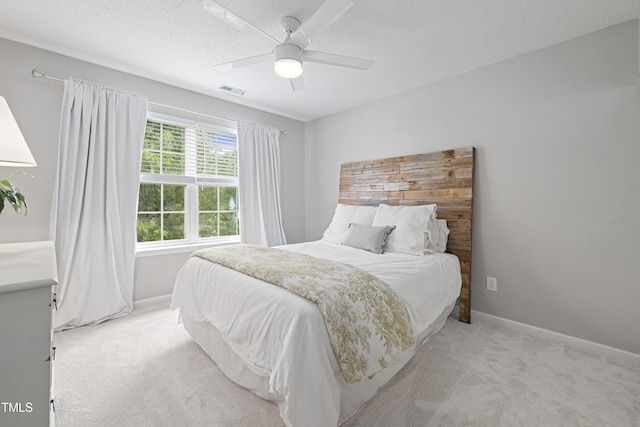 bedroom featuring baseboards, light carpet, and a textured ceiling