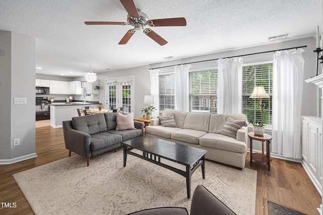 living area featuring a textured ceiling, ceiling fan, wood finished floors, and a healthy amount of sunlight