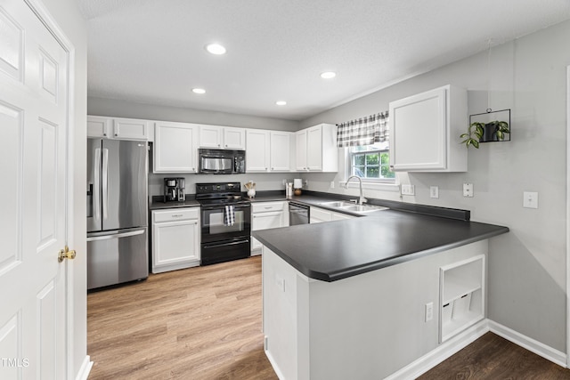 kitchen with a sink, dark countertops, black appliances, and white cabinetry