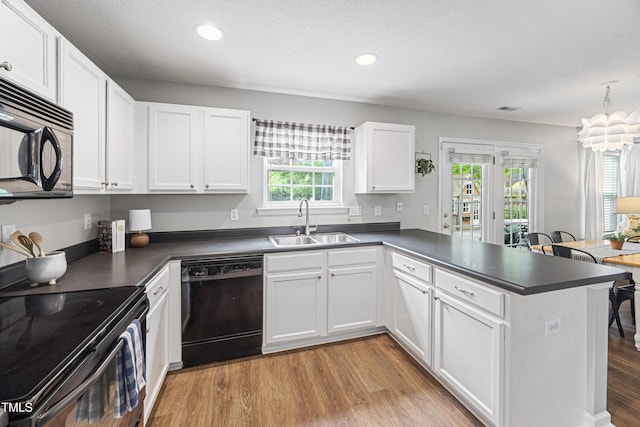 kitchen featuring a sink, dark countertops, black appliances, and a peninsula