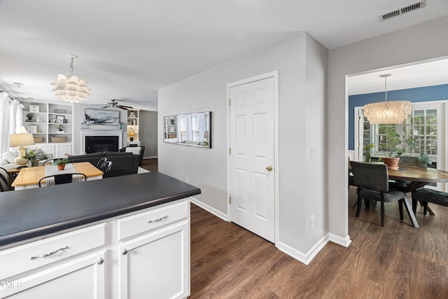 kitchen featuring visible vents, dark countertops, white cabinets, ceiling fan with notable chandelier, and dark wood-style floors
