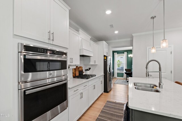 303 Forestview Crest Way, Fuquay Varina, NC 27526 - kitchen featuring appliances with stainless steel finishes, light wood-type flooring, a sink, custom exhaust hood, and ornamental molding