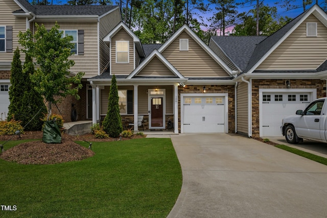 106 Churment Ct, Durham, NC 27703 - view of front facade featuring stone siding, covered porch, concrete driveway, a garage, and a lawn