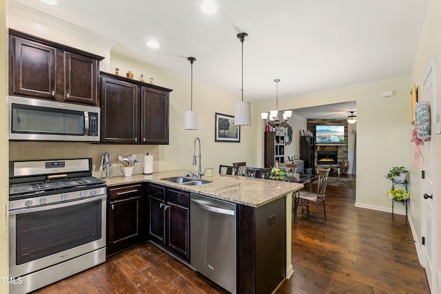 106 Churment Ct, Durham, NC 27703 - kitchen with light stone counters, stainless steel appliances, dark brown cabinets, a sink, and a peninsula