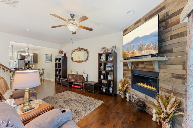 106 Churment Ct, Durham, NC 27703 - living area featuring dark wood finished floors, a stone fireplace, visible vents, and ceiling fan with notable chandelier