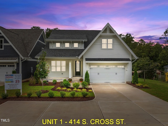 view of front of property featuring a garage, a shingled roof, driveway, and a front yard