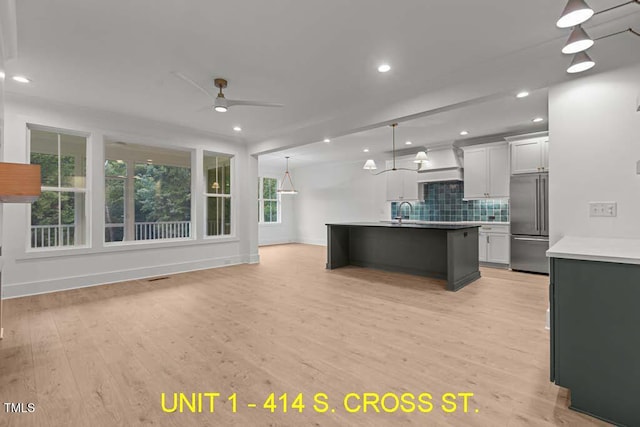 kitchen featuring ceiling fan, high end refrigerator, open floor plan, light wood-type flooring, and backsplash