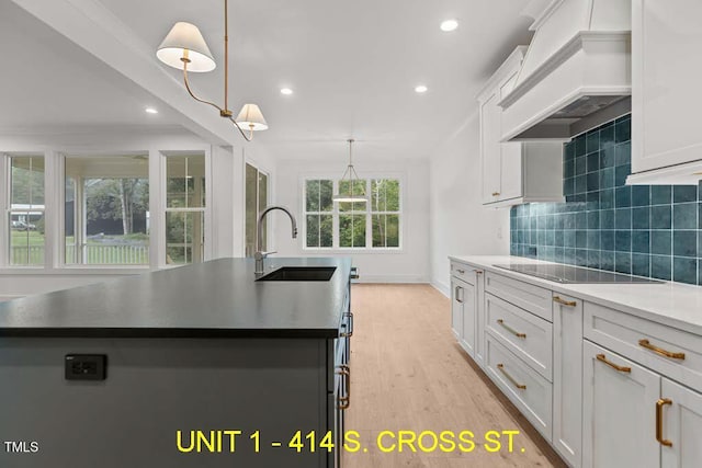 kitchen with a kitchen island with sink, recessed lighting, a sink, and premium range hood