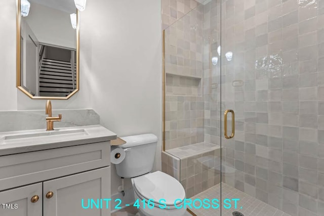 bathroom featuring vanity, toilet, and a shower stall