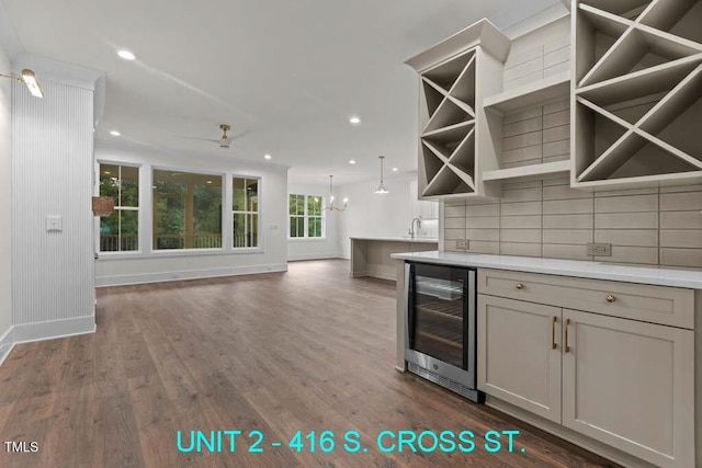 bar featuring dark wood-style flooring, beverage cooler, baseboards, recessed lighting, and a sink