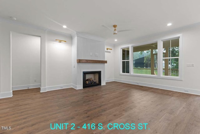 unfurnished living room featuring dark wood-style flooring, ceiling fan, a large fireplace, and baseboards