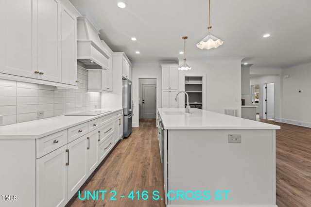 kitchen featuring freestanding refrigerator, custom exhaust hood, a center island with sink, recessed lighting, and a sink