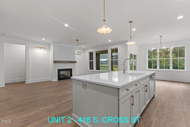 kitchen featuring a fireplace, baseboards, a sink, and wood finished floors