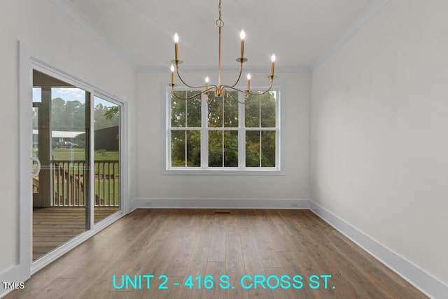 unfurnished dining area featuring crown molding, baseboards, wood finished floors, and a chandelier