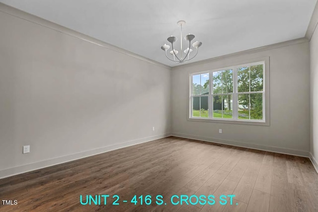unfurnished room with an inviting chandelier, baseboards, ornamental molding, and wood finished floors