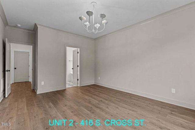 spare room featuring baseboards, a chandelier, and wood finished floors