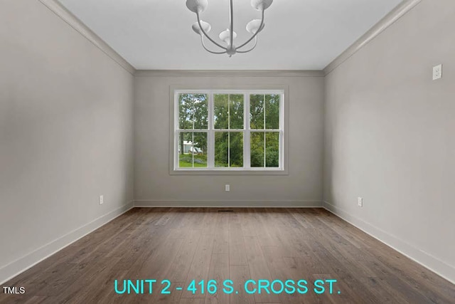 spare room featuring an inviting chandelier, baseboards, and wood finished floors