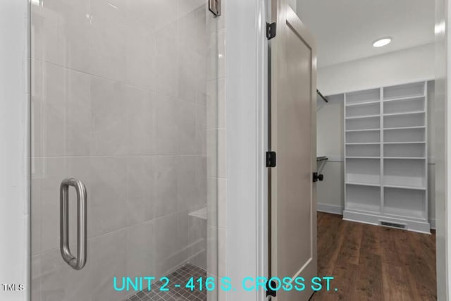 bathroom with visible vents, a shower stall, a walk in closet, and wood finished floors